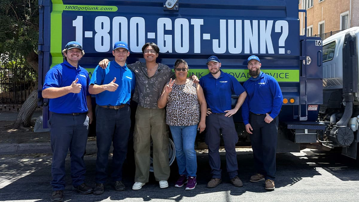 Jose Ruiz, his mom, and the 1-800-GOT-JUNK? team smiling in front of the truck.