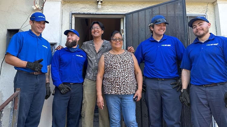 Jose Ruiz, his mom, and the 1-800-GOT-JUNK? team smiling in front of a newly decluttered home.