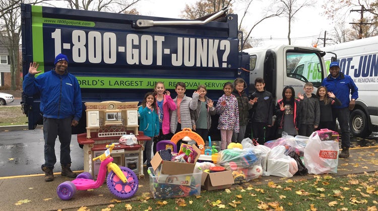 Children with toy donations in front of a 1-800-GOT-JUNK? truck