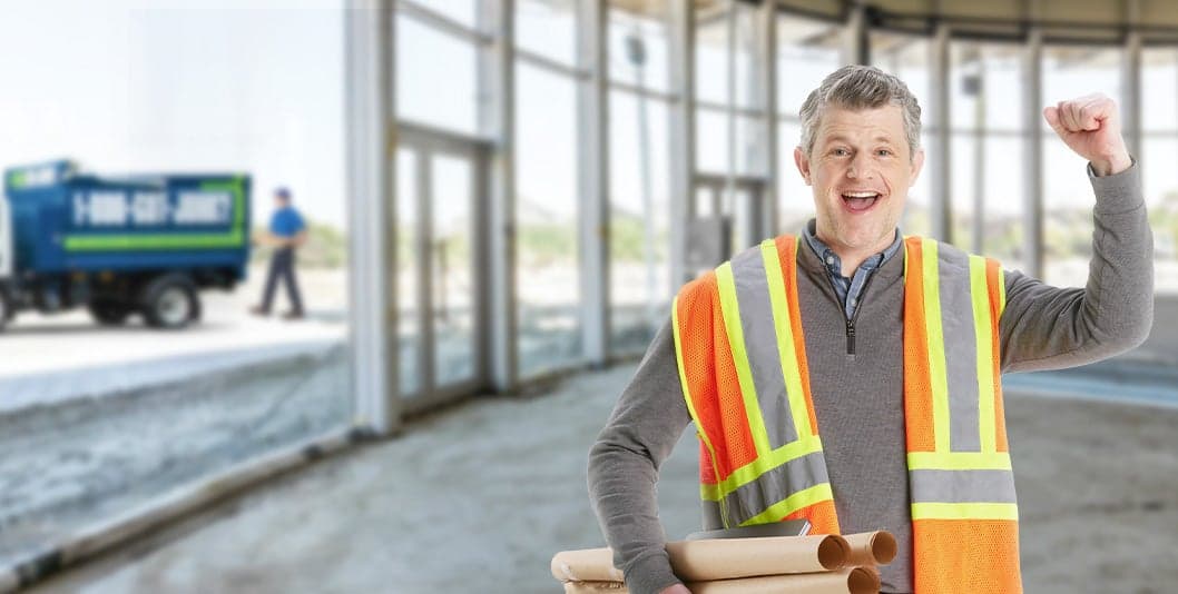 happy contractor at decluttered site with junk removal truck