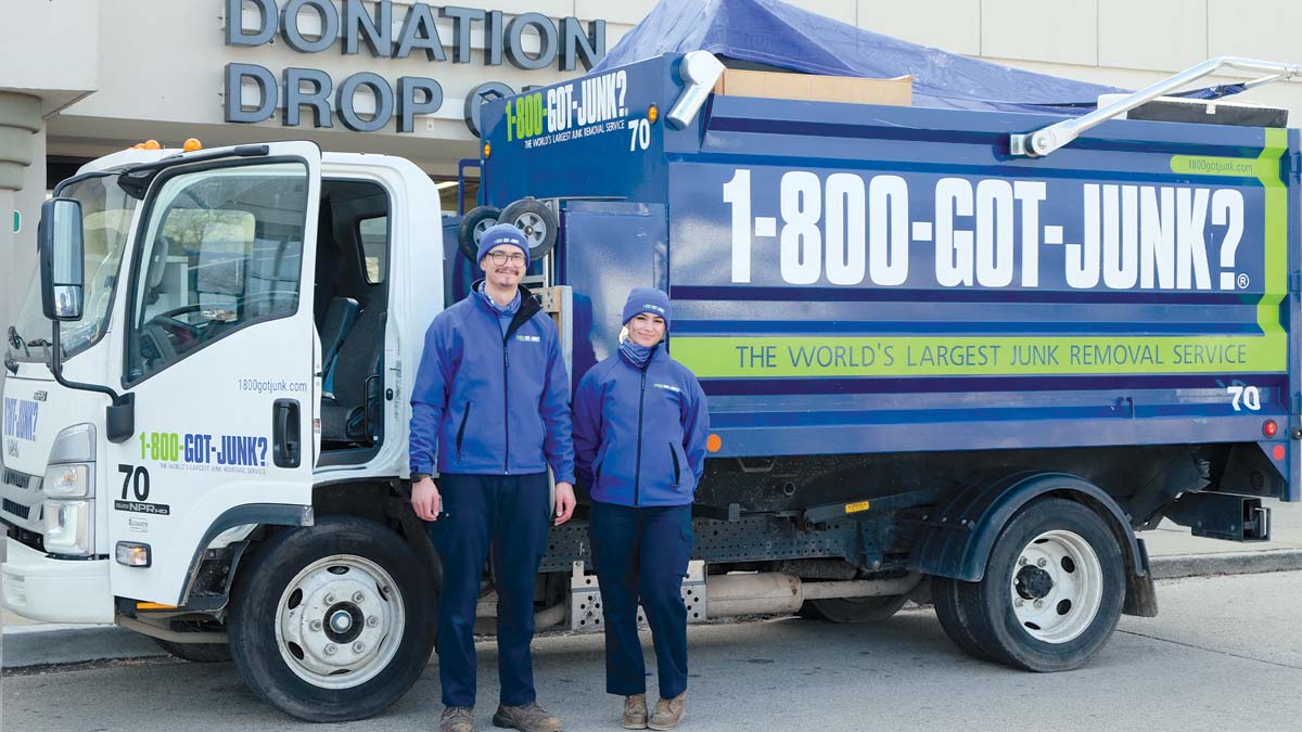 Two truck team members standing in front of 1-800-GOT-JUNK? truck at donation drop off facility