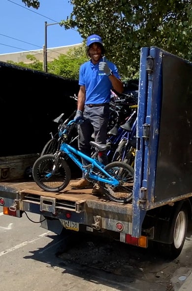 1-800-GOT-JUNK? team member putting bicycle in back of truck for bicycle recycling