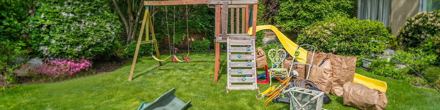 Old child's playset in a backyard with junk that needs to be removed