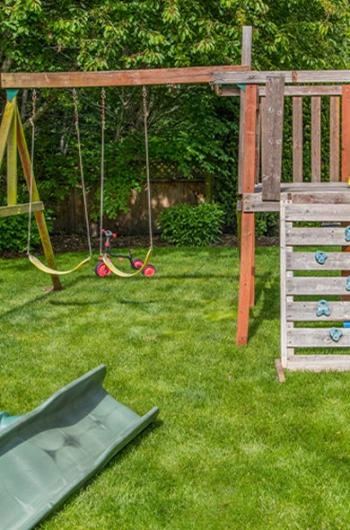 Old child's playset in a backyard with junk that needs to be removed