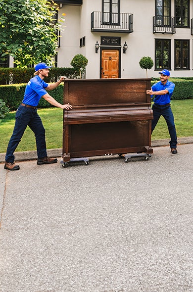 Two 1-800-GOT-JUNK? team members picking up a piano for removal and donation