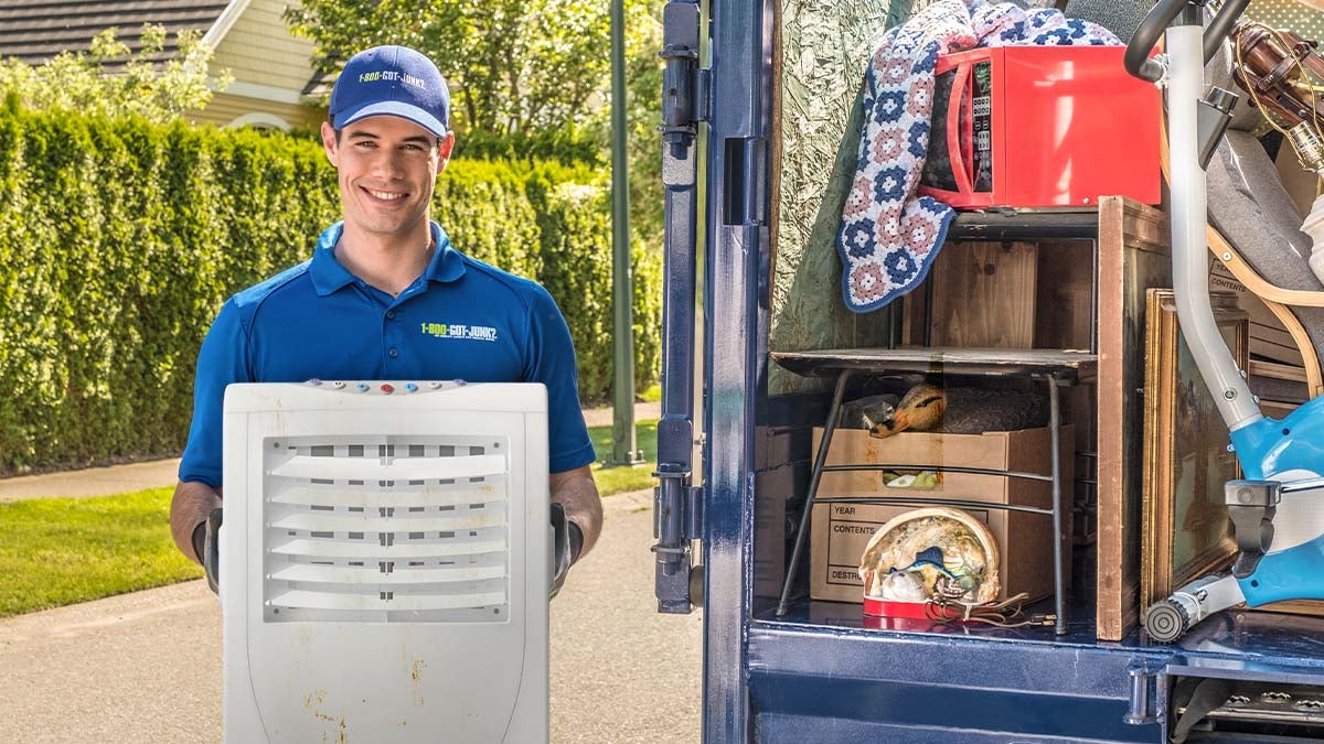 1-800-GOT-JUNK? truck team member holding dehumidifier beside truck