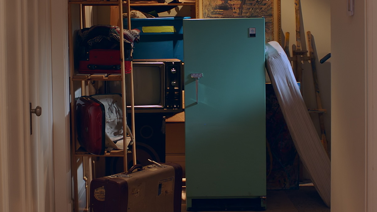 An old refrigerator surrounded by junk waiting to be disposed.