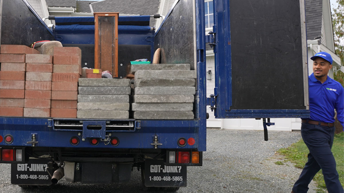 1-800-GOT-JUNK? truck team members loading concrete bricks and pavers onto the truck bed.