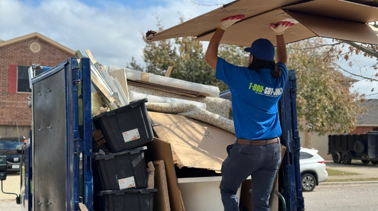 1-800-GOT-JUNK? team member loading a large piece of cardboard to a junk removal truck