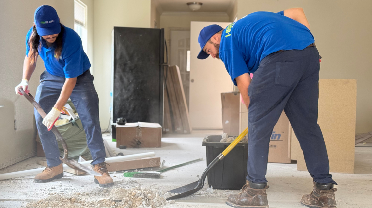 1-800-GOT-JUNK? truck team members shovelling renovation debris out of a customer's home