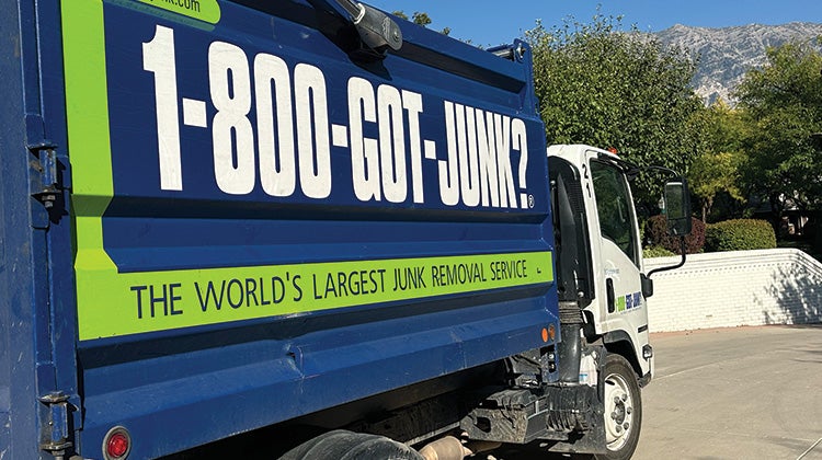 Image of a 1-800-GOT-JUNK? truck parked outside a house