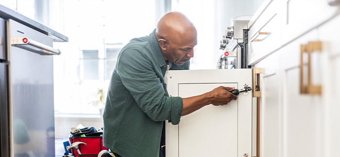 A man removing his cabinet doors from his kitchen.