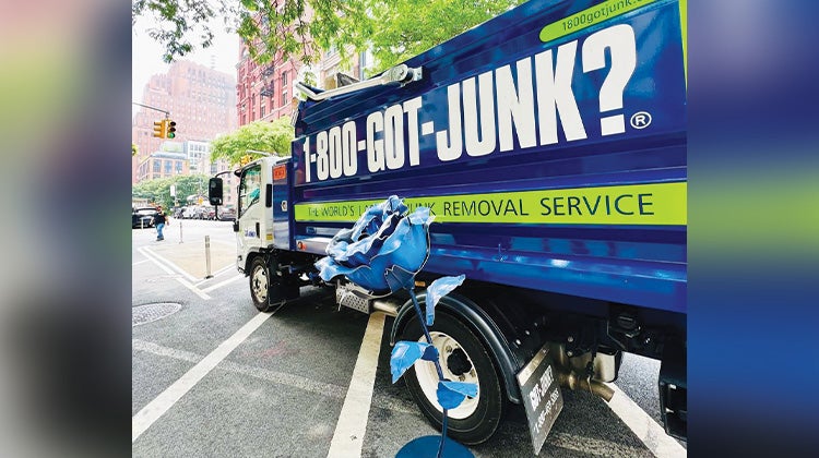 Giant blue rose leaning agains a 1-800-GOT-JUNK? truck