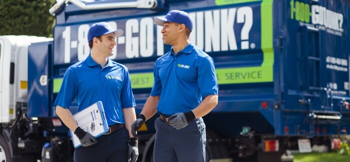 Two 1-800-GOT-JUNK? team members standing in front of a 1-800-GOT-JUNK? truck.