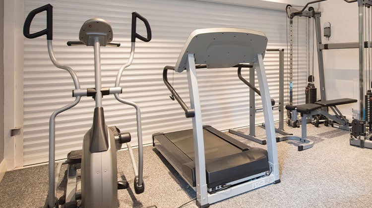 Old treadmill surrounded by outdated exercise equipment in gym