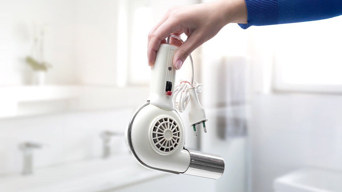 Hand holding an outdated hairdryer in a clean bright space