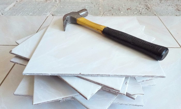 Hammer resting on a stack of old white floor tiles