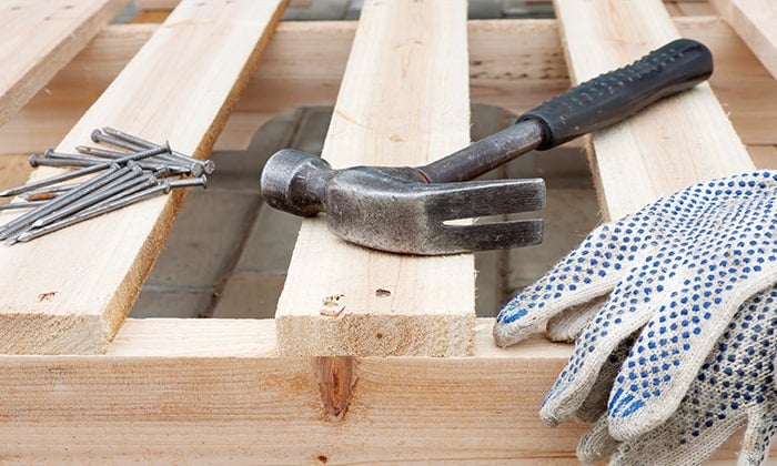 Nails, hammer and gloves resting on a pallet