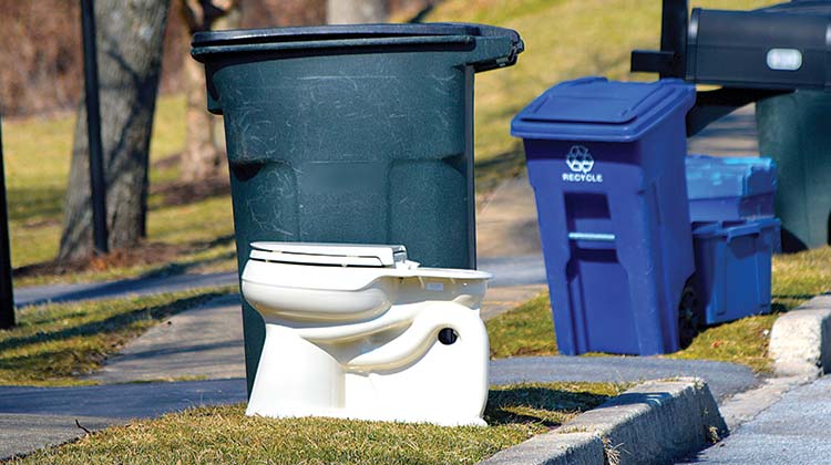 An old toilet sitting at the curbside, ready to be picked up