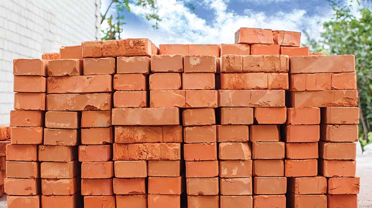 Stack of red bricks in a residential backyard