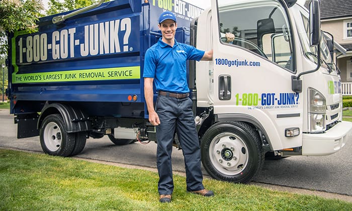 1-800-GOT-JUNK? truck team member standing in front of branded truck in residential neighborhood