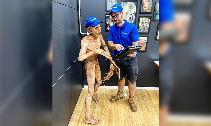 A 1-800-GOT-JUNK? Truck Team Member by a zombie statue.